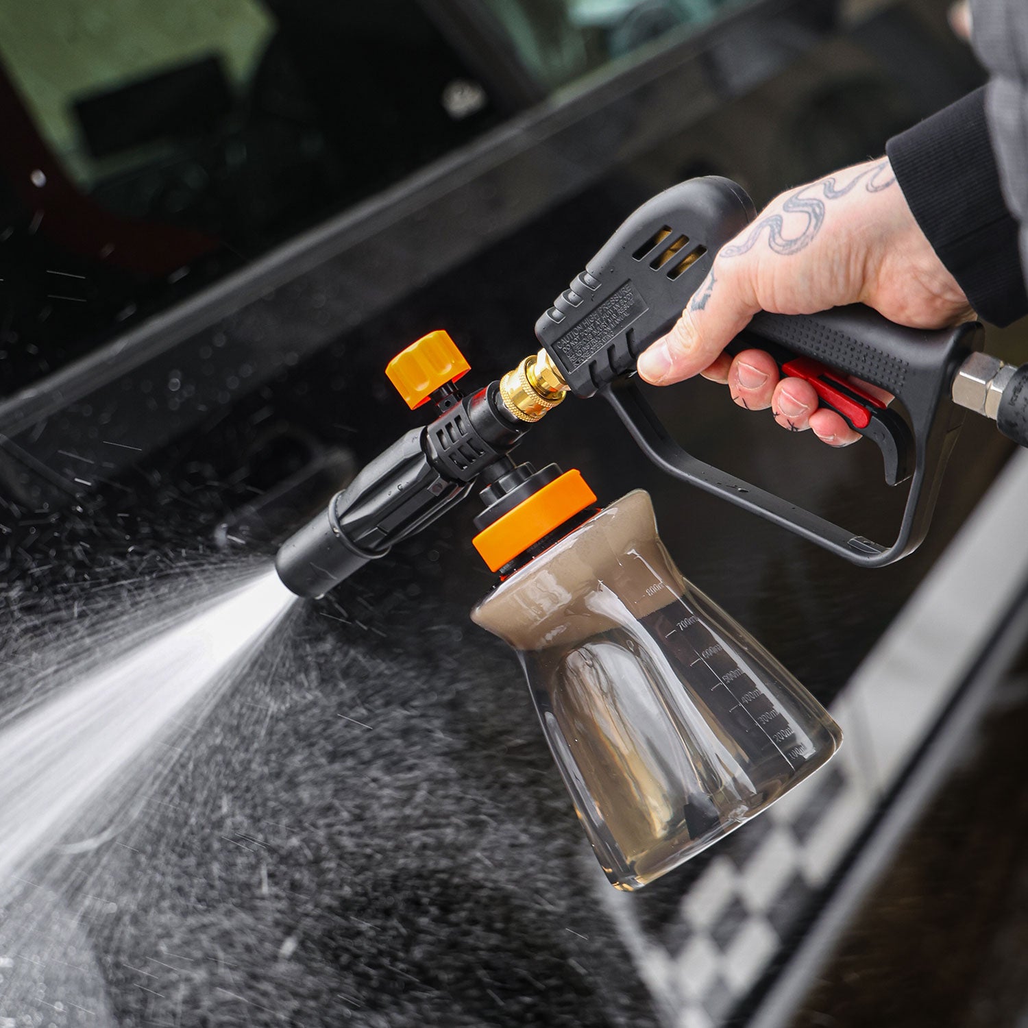 Person using a high-pressure snow foam lance to clean a car