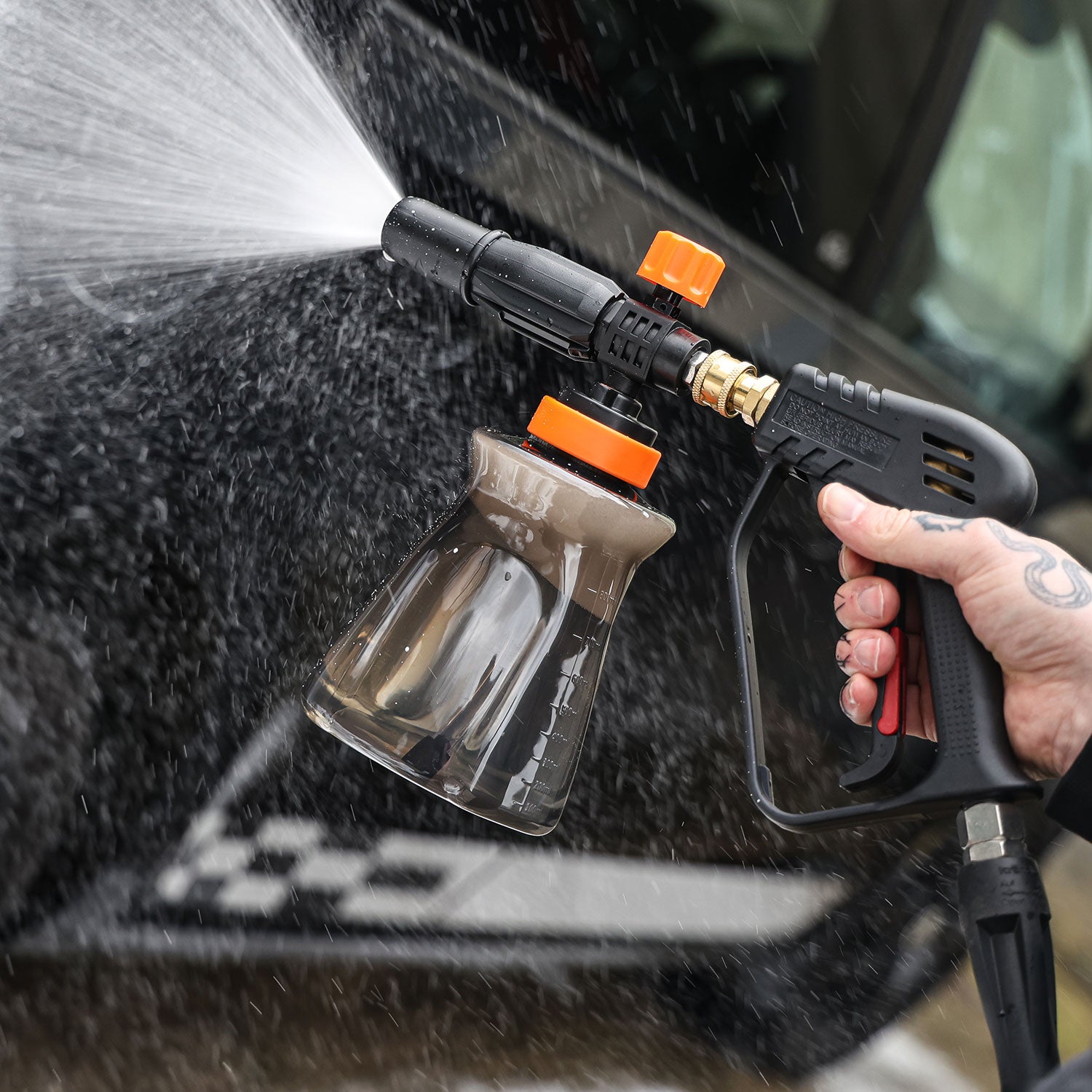 Person using a high-pressure snow foam lance to clean a car