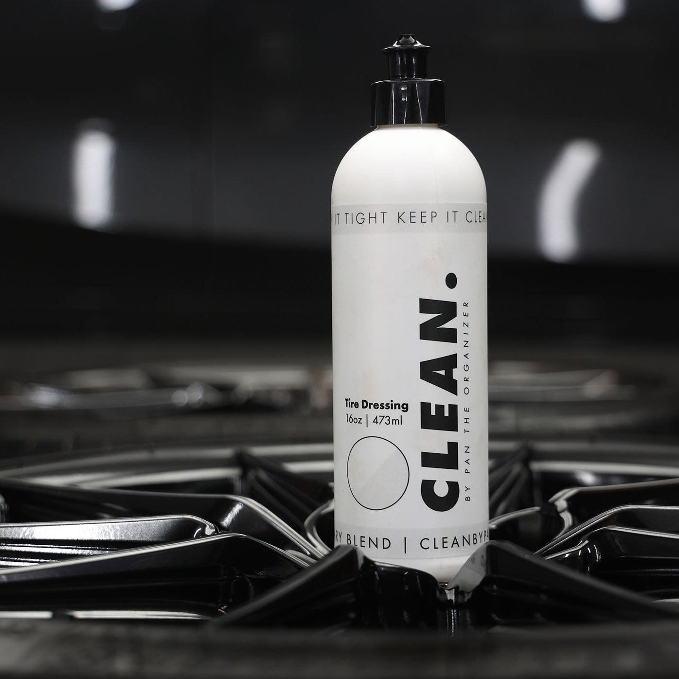 Bottle of 'Clean' tyre dressing on a metallic surface with a dark background