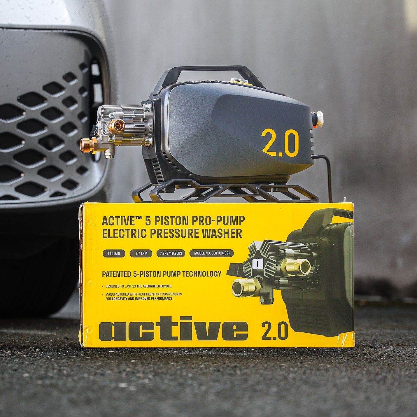 Electric pressure washer with 'active 2.0' packaging in front of a car.