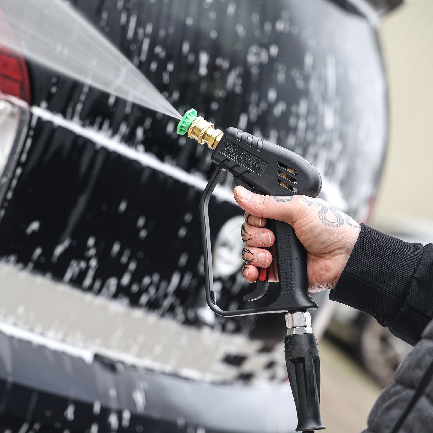 Person using a high-pressure washer stubby gun to clean a car