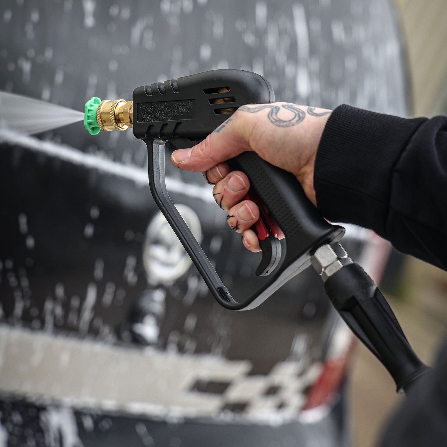 Person using a pressure washer stubby gun to clean a car