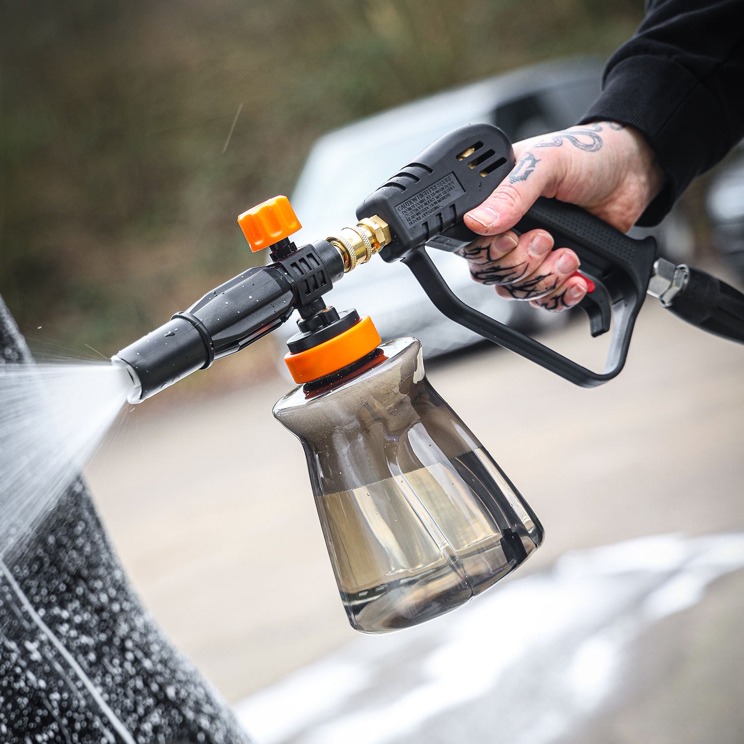 Person using a snow foam lance to clean a car
